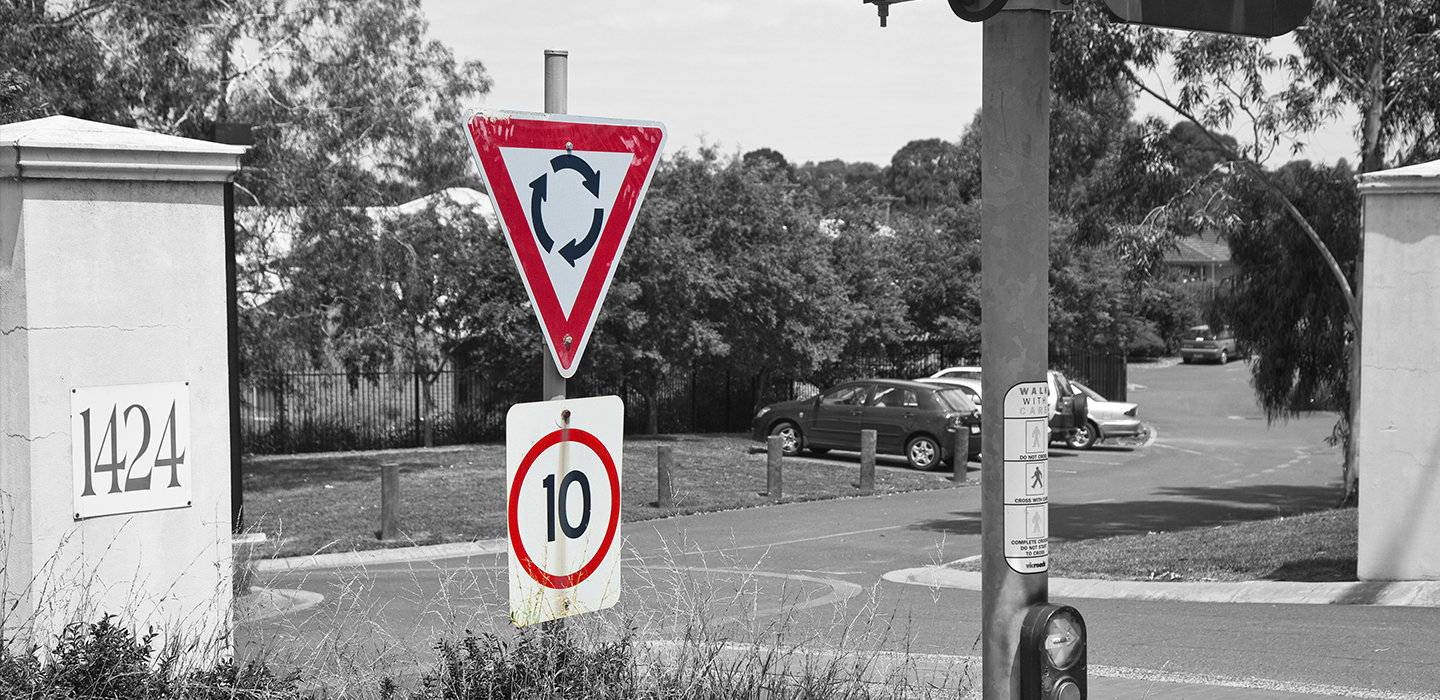 A roundabout sign and speed sign showing 10km per hour