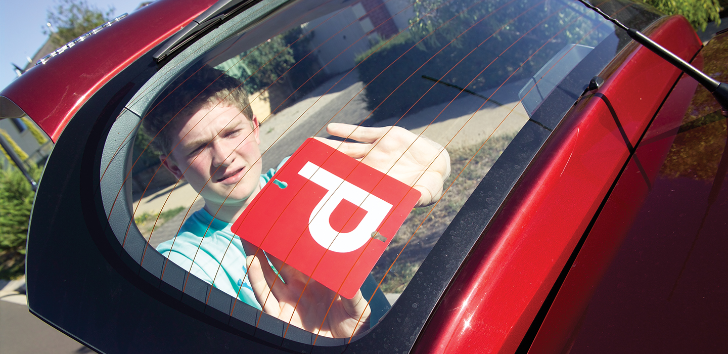 A P plater putting red P plates on their car