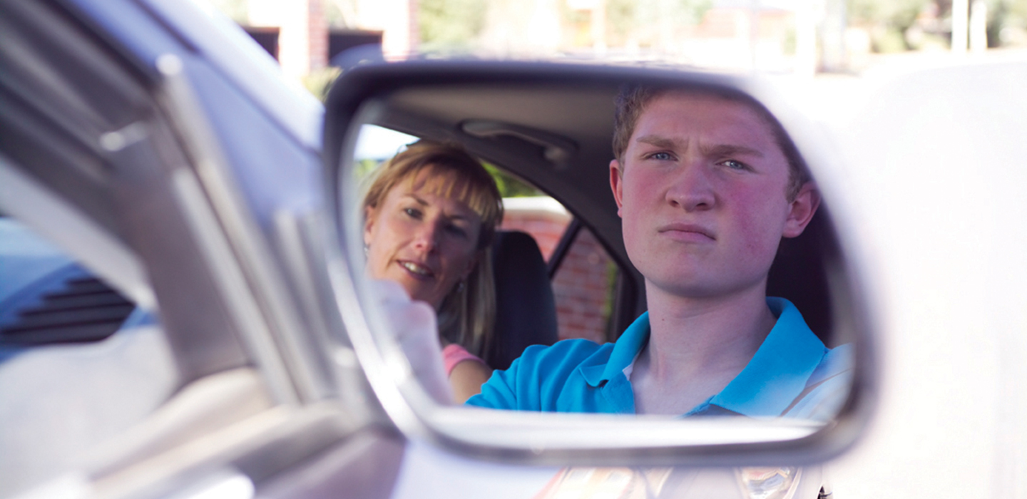 A learner looking into their side view mirror